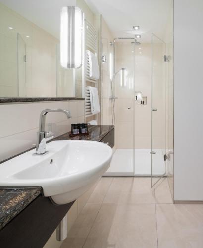 a white bathroom with a sink and a shower at Hotel zur Post Riesenbeck in Riesenbeck