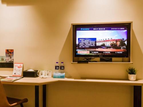 a desk with a tv on a wall with a desk sidx sidx sidx at GreenTree Inn Anhui Xuancheng South Zhuangyuan Road Express Hotel in Xuanzhou
