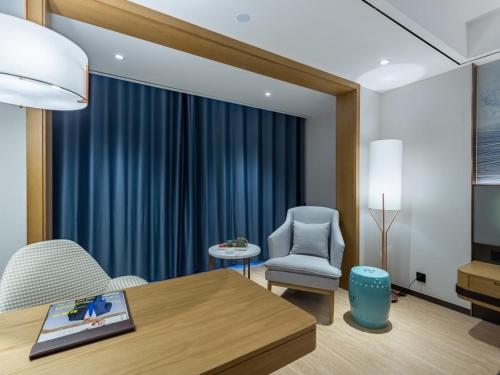 a living room with a table and a chair at GreenTree Eastern Xuzhou High Speed Railway Station Square Yindi Automobile Market Hotel in Xuzhou