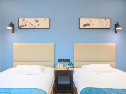 two beds in a room with blue walls at GreenTree Inn Henan Kaifeng Gulou Square Express hotel in Kaifeng