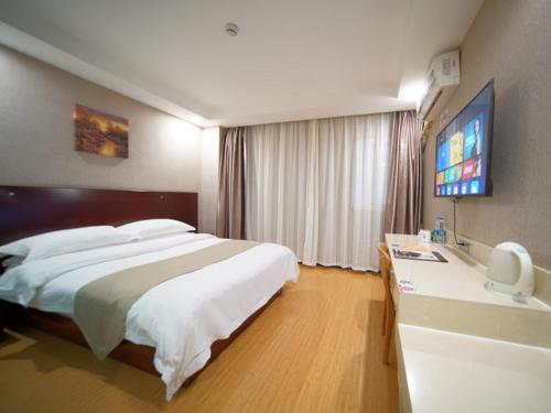 a bedroom with a large bed and a flat screen tv at GreenTree Inn Shanghai Baoshan Yanghang Shuichan Road Hotel in Baoshan
