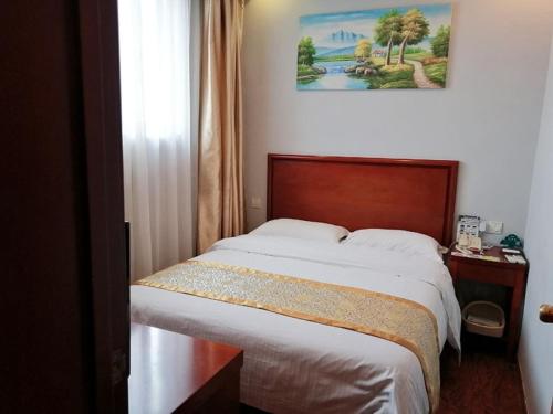 a bedroom with a bed and a picture on the wall at GreenTree Inn Shanghai Meilan Lake Hutai Road Express Hotel in Baoshan