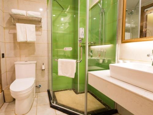 a green bathroom with a toilet and a sink at GreenTree Inn Maanshan East Railway Station Oushang Supermarket Business Hotel in Fengqiao