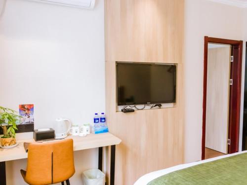 a room with a tv and a desk with a chair at GreenTree Inn Anhui Xuancheng South Zhuangyuan Road Express Hotel in Xuanzhou