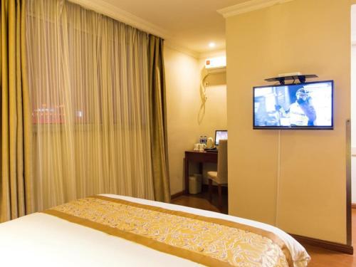 a hotel room with a bed and a flat screen tv at GreenTree Inn Jiangsu Taizhou Jingjiang Bus Station Express Hotel in Jingjiang