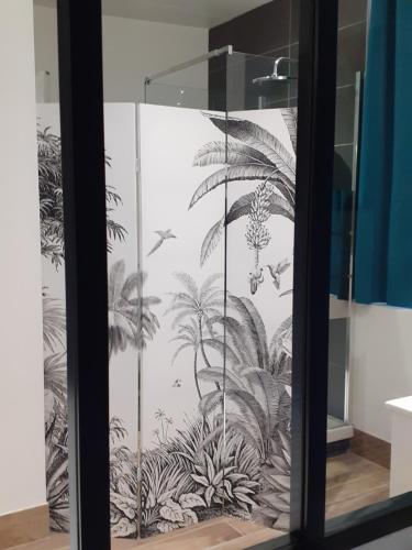 une porte en verre avec une fresque murale représentant des plantes dans l'établissement Tropical loft, au Puy-en-Velay