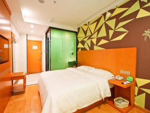 a bedroom with a large white bed and a green wall at Vatica Hefei Yaohai District Wangang Road Metro Station Hotel in Hefei