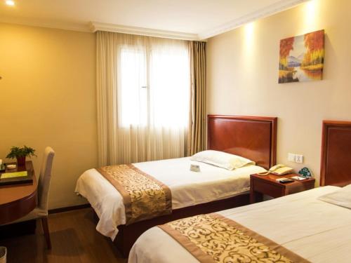 a hotel room with two beds and a window at GreenTree Inn Jiangsu Taizhou Jingjiang Bus Station Express Hotel in Jingjiang