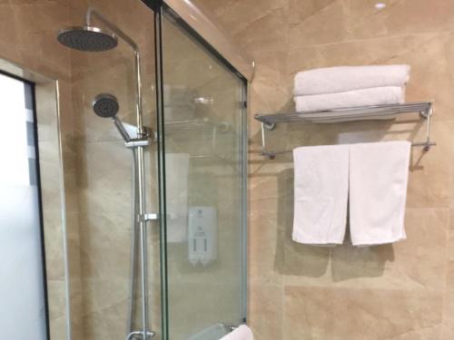 a bathroom with a glass shower and towels at GreenTree Alliance Bengbu Railway Station Hotel in Bengbu