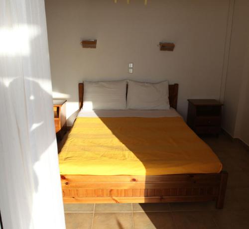 1 dormitorio con cama de madera y manta amarilla en Il Villaggio, en Chrani