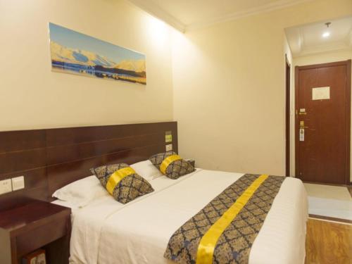 a bedroom with a bed with yellow and black pillows at GreenTree Inn Tianjin Huanghe Ave Guangkai Metro Station Express Hotel in Tianjin