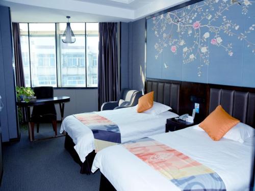 安慶市にあるShell Anqing City Yingjiang District Renmin Road Pedestrian Street Hotelのベッド2台とデスクが備わるホテルルームです。
