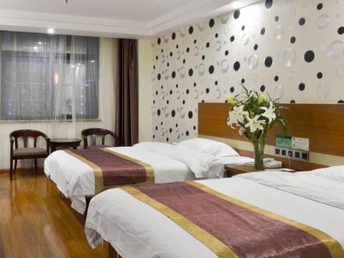 a hotel room with two beds and a vase of flowers at GreenTree Alliance Shandong Linyi Mengyin Xincheng road Hotel in Mengyin