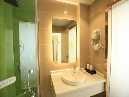 a bathroom with a sink and a mirror and a shower at GreenTree Inn Anqing City Yixiu Government District University City Express Hotel in Anqing