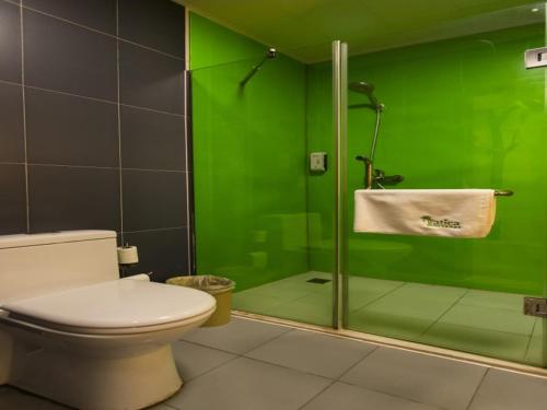 a green bathroom with a toilet and a glass shower at Vatica Bozhou City Railway Station Hotel in Bozhou
