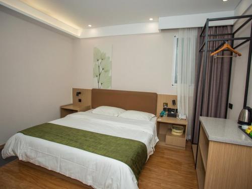 a bedroom with a large bed and a desk at GreenTree Inn Lu'an Kaihong Plaza Express Hotel in Lu'an