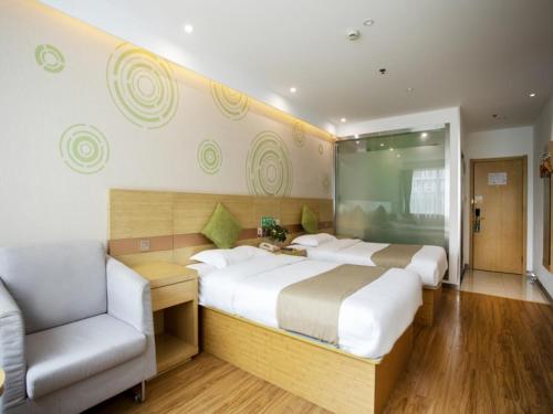 a large bedroom with two beds and a chair at GreenTree Inn Shanghai Minhang District Lianhang Road Subway Station Express Hotel in Shanghai