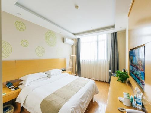 a hotel room with a large bed and a desk at GreenTree Inn Jiangyin Bus Station Meiyuan Street Express Hotel in Wuxi
