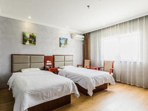 a hotel room with two beds and a window at GreenTree Inn Shanghai Huinan Jinghai Road Express Hotel in Nanhui