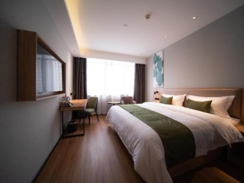Un dormitorio con una cama y un escritorio y una ventana. en GreenTree Inn Anhui Hefei Mengcheng Road Beierhuan Express Hotel, en Hefei