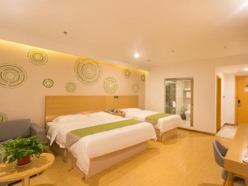 a hotel room with two beds and a couch at GreenTree Inn Suzhou Tai Lake Xukou Town Government Express Hotel in Suzhou