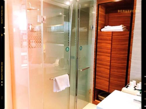 a shower with a glass door in a bathroom at GreenTree Alliance AnHui HeFei MengCheng North Road JiQiao Road Hotel in Hefei