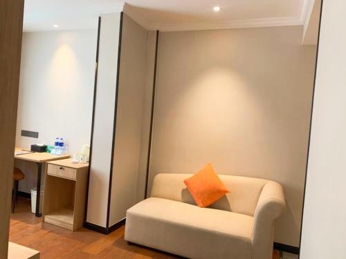 a living room with a couch with an orange pillow at GreenTree Inn Anhui Xuancheng South Zhuangyuan Road Express Hotel in Xuanzhou