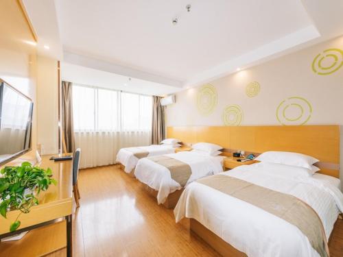 a hotel room with four beds and a flat screen tv at GreenTree Inn Jiangyin Bus Station Meiyuan Street Express Hotel in Wuxi