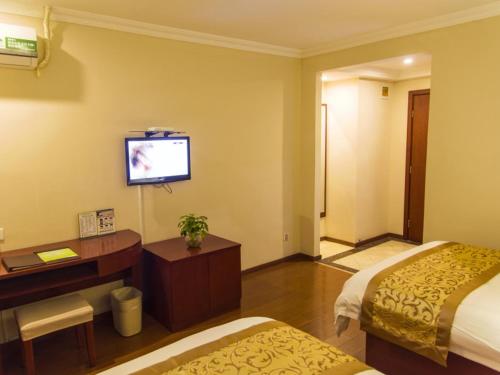a hotel room with two beds and a desk and a television at GreenTree Inn Jiangsu Taizhou Jingjiang Bus Station Express Hotel in Jingjiang