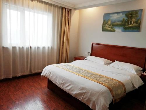 a bedroom with a large bed and a window at GreenTree Inn Shanghai Meilan Lake Hutai Road Express Hotel in Baoshan