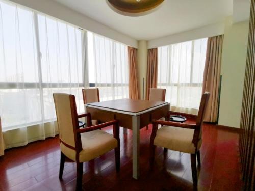 a dining room table and chairs in a room with windows at GreenTree Inn Jiangsu Suzhou Taicang Liuhe Passenger Station Express Hotel in Taicang