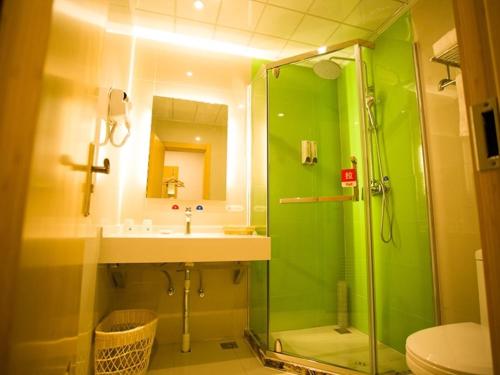 a green bathroom with a sink and a shower at GreenTree Inn Yongnian County Hebei Shop Express Hotel in Handan