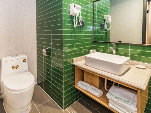 a green tiled bathroom with a toilet and a sink at GreenTree Inn Dalian Airport New District Xinzhaizi Express Hotel in Dalian
