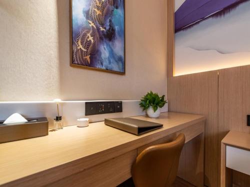 a desk in a room with a picture on the wall at VX Xuzhou Yunlong District Normal University Yunlong Mountain Scenic Spot Hotel in Xuzhou