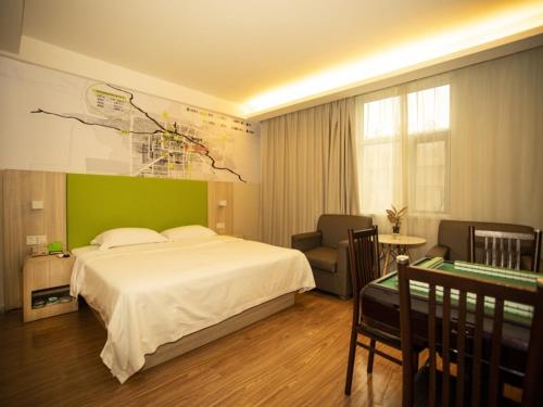 - une chambre avec un lit blanc et un mur vert dans l'établissement Vatica Bozhou City Railway Station Hotel, à Bozhou