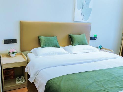 a bedroom with a large bed with green pillows at GreenTree Inn Anhui Xuancheng South Zhuangyuan Road Express Hotel in Xuanzhou