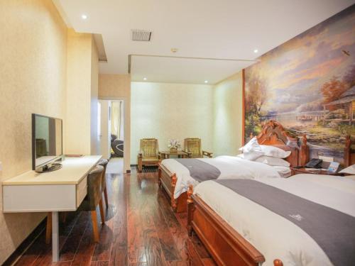 een hotelkamer met 2 bedden en een bureau met een televisie bij GreenTree Inn Guangxi Guilin Railway Station Business Hotel in Guilin