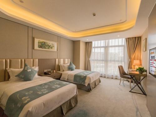 a hotel room with two beds and a desk at GreenTree Eastern Wuxi Xinwu District Airport Road Hotel in Wuxi