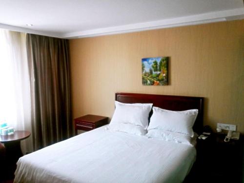 a bedroom with a large bed with white pillows at GreenTree Inn Anhui Chuzhou International Market Place Express Hotel in Chuzhou