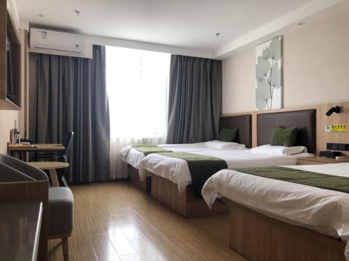 a hotel room with two beds and a desk at GreenTree Inn Heze Dingtao District Auto Town in Heze