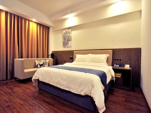 a bedroom with a large bed and a couch at GreenTree Inn Dongfang City Dongfang Avenue High-speed Railway Station Express Hotel in Dongfang