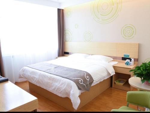 a bedroom with a bed and a desk and a window at GreenTree Inn Baoding Gaobeidian Baigou Express Hotel in Baoding