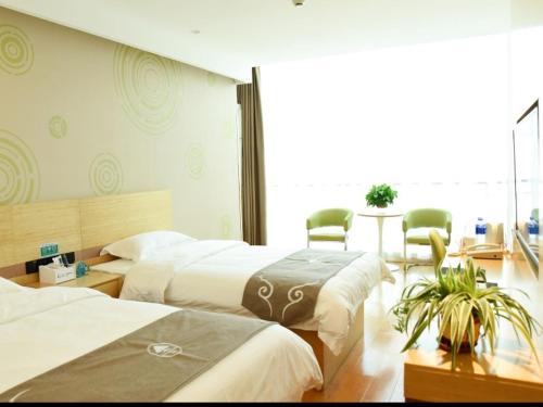 a hotel room with three beds and a table at GreenTree Inn Baoding Gaobeidian Baigou Express Hotel in Baoding