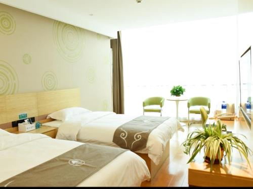 Habitación de hotel con 3 camas y mesa en GreenTree Inn Baoding Gaobeidian Baigou Express Hotel, en Baoding