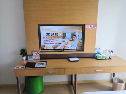 a tv on top of a wooden desk in a room at GreenTree Inn Shanghai Jinshan District Wanda Plaza Longhao Road Express Hotel in Nanhui