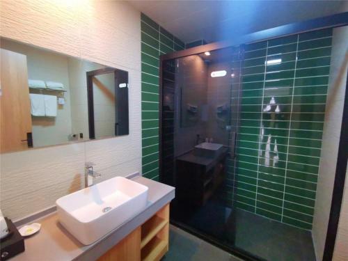 a bathroom with a sink and a shower with green tile at GreenTree Inn Heze Dingtao District Auto Town in Heze