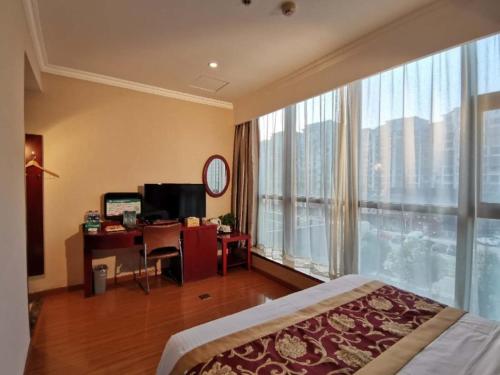 a bedroom with a bed and a desk and a large window at GreenTree Inn Wuxi New District Hongshan Town Commercial Square Shell Hotel in Dongkunqiao