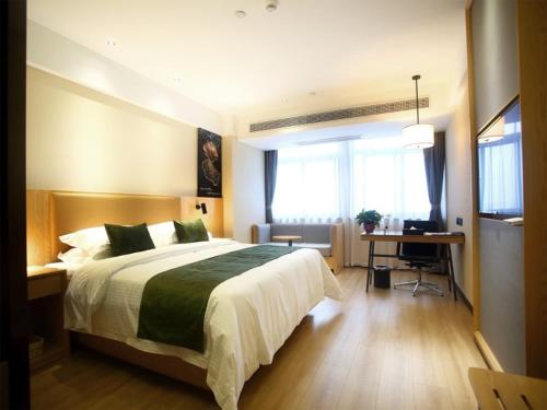 a bedroom with a large bed and a desk in it at GreenTree Inn Fuyang Exhibition Center Business Hotel in Fuyang