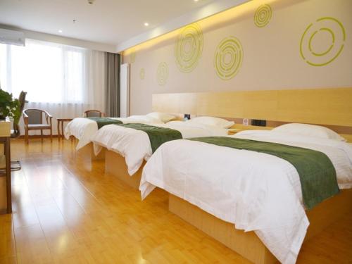 a hotel room with four beds with white sheets at GreenTree Inn Beijing Yanqing District Badaling Changcheng Kangzhuang Smart Choice Hotel in Yanqing