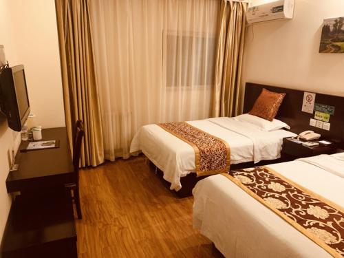 a hotel room with two beds and a television at GreenTree Inn Tianjin Huanghe Ave Guangkai Metro Station Express Hotel in Tianjin